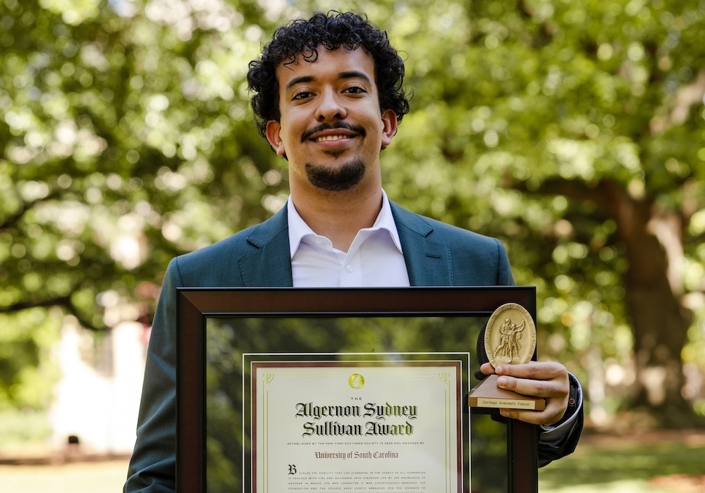 man in white shirt and blue suit holding framed award