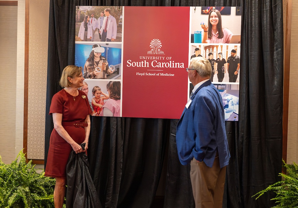 Two people unveil a sign reading "floyd school of medicine"