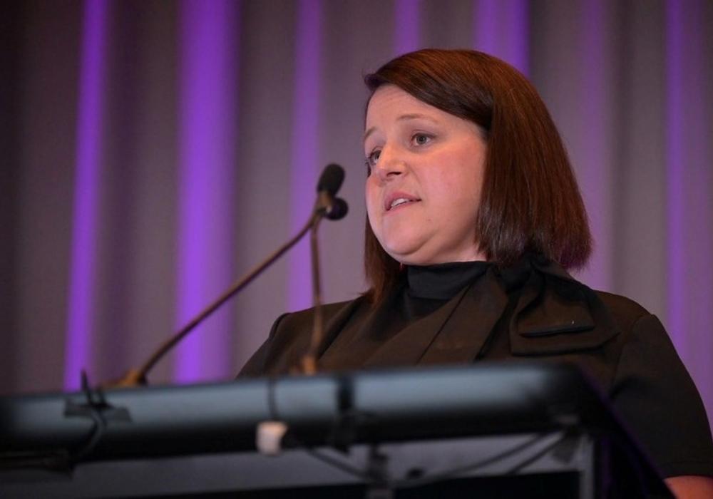 Laura Ashley Thomas speaks from a pedestal at an awards banquet