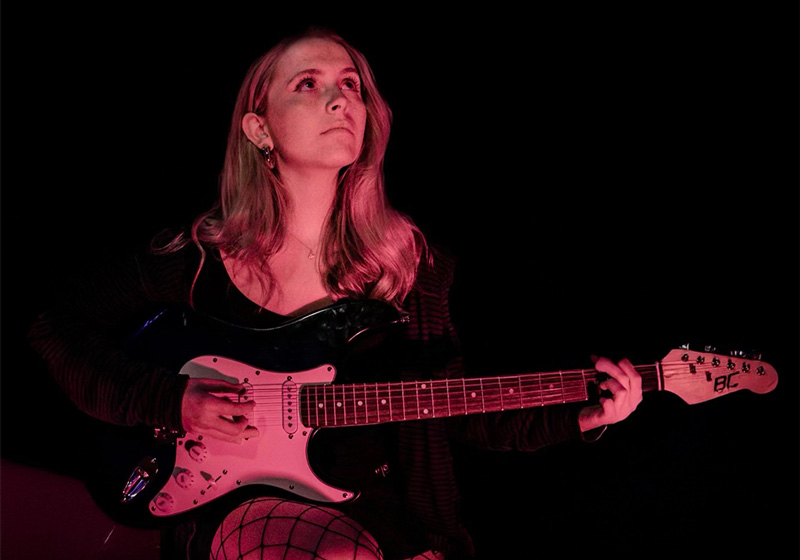 a woman plays an electric guitar