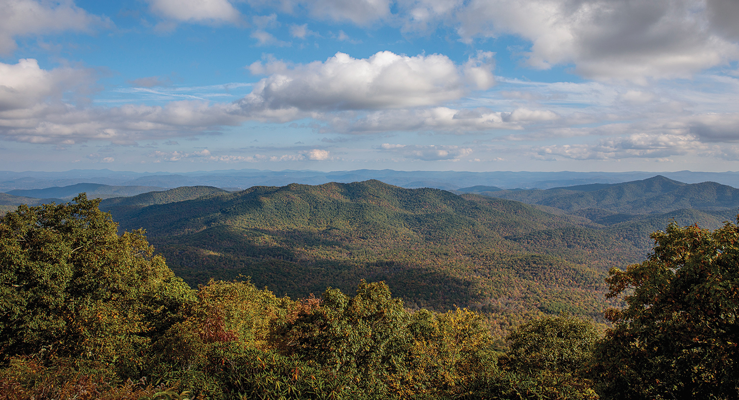 Overlook at the Blue Ridge Parkway with views of the mountains and a beautiful blue sky. 