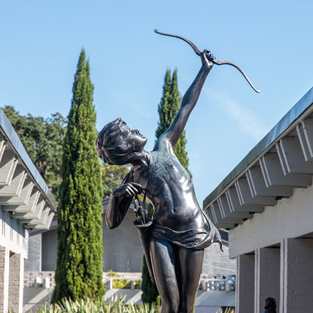 Statue of a person aiming a bow and arrow towards the sky. 