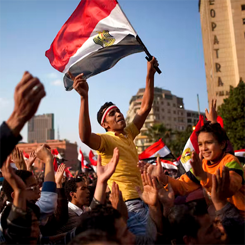 Man in crowd waving Syrian flag