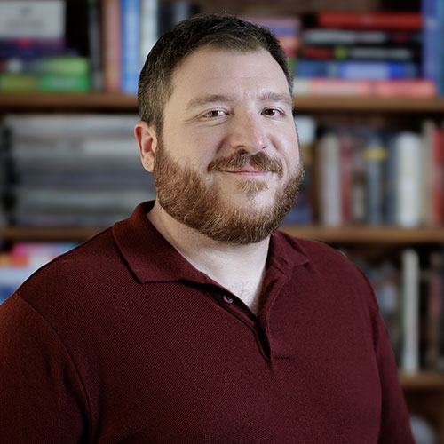 A headshot of Patrick Pianezza in front of a bookshelf