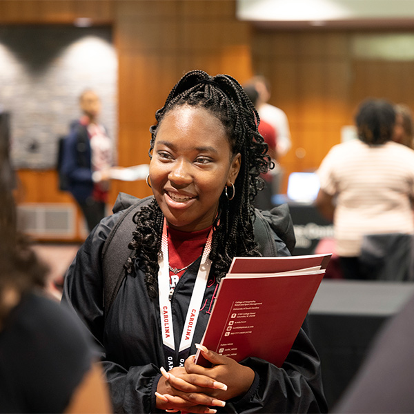 Student at Summer Seniors camp stands at table at academic fair