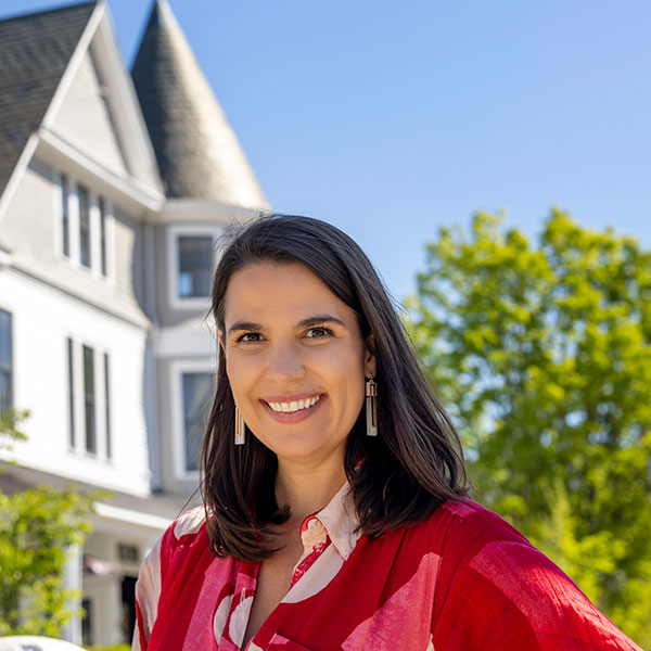 woman stands in front of a historic home
