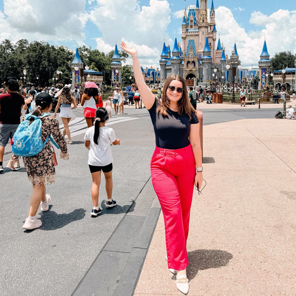 Woman with arm up in front of Walt Disney World castle