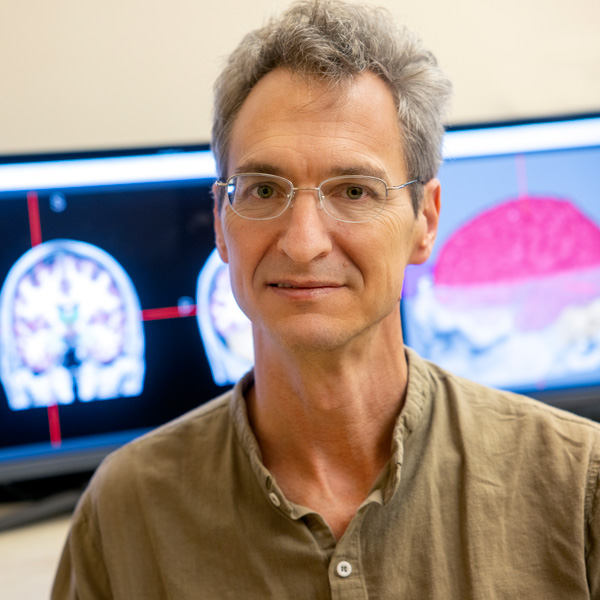 Man stands in front of brain scans on computer terminals