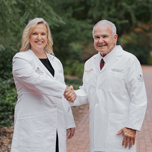 Dr. Phyllis MacGilvray and Dr. Gerald Harmon shake hands on USC's Columbia campus.
