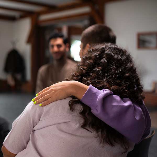 Person sits with their arm around another person