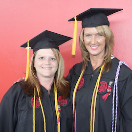 Kristal Tribble and Tina Williamson pose in their caps and gowns after graduating from the online RN to BSN program.