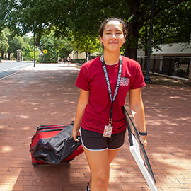 New student pulls her suitcase behind her on Greene Street as she moves in.
