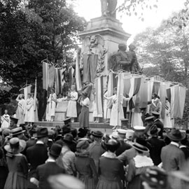 women with banners stand by a monument in Washington D.C. in 1918 to advocate for women's suffrage