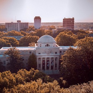A drone photo that is a bird's eye view of campus, specifically focused on the McKissick Museum surrounded by vibrant fall orange and yellow foliage