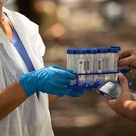 a lab worker holding saliva test tubes