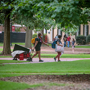 A family taking a cart across the Horseshoe during Move-In 2021