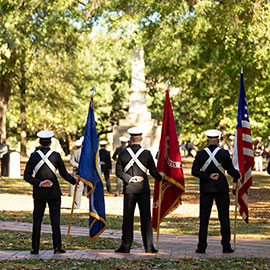 People in service uniforms stand with flags on the historic Horseshoe