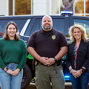 Olivia Darr, Chief Maron Boyce and Rhonda DiNovo stand in front of a police vehicle. 