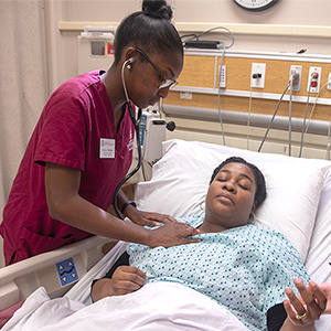 Nursing student listening to a patients heartbeat.