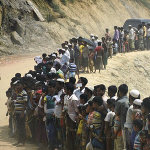 myanmar refugees form a long line in a desert environment
