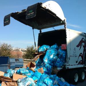 a large trash truck filled with blue trash bags