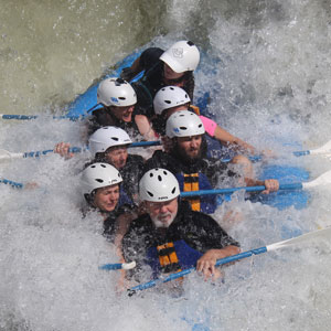 Group of people wearing helmets white water rafting