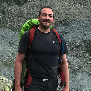 Besim Dragovic stands with backpack in the Swiss Alps.
