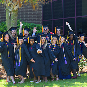 Group of students posing for a picture outside in graduation regalia