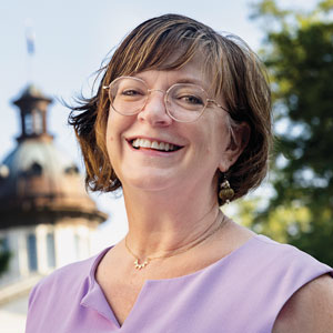 A portrait of Sara Barber with SC Statehouse in the background.
