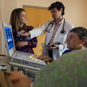 Physician and medical student look at computer screen