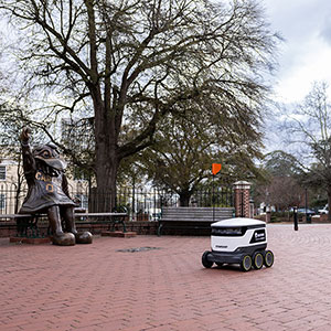 A Starship delivery robot rolling past the Cocky statue near Greene Street