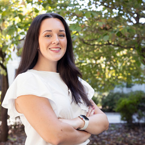 woman stands outside with greenery in the background