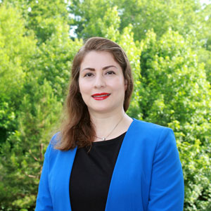 woman stands outside in front of greenery