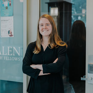 Woman standing with her arms crossed over her chest in front of glass door 