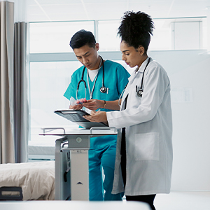 A doctor and nurse review a chart together in a hospital room