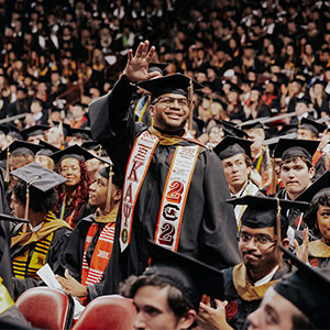 Student stands and waves at commencement cermony