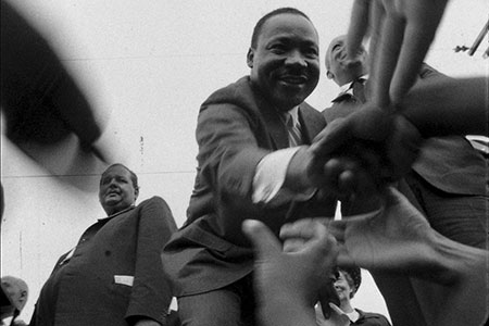 Martin Luther King Jr. clasps hands with attendees