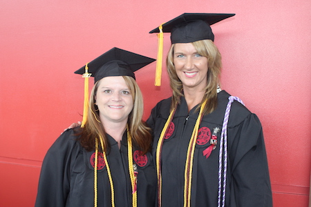 Kristal Tribble and Tina Williamson in their graduation caps and gowns
