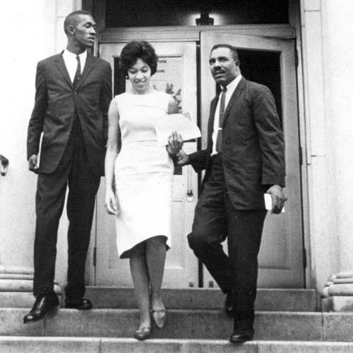 two men and a woman stand on the steps of a building