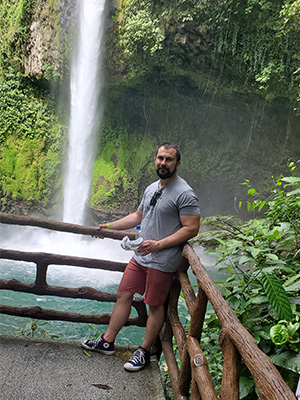 Jason Czerwinski stands at a railing with La Paz waterfall behind him.