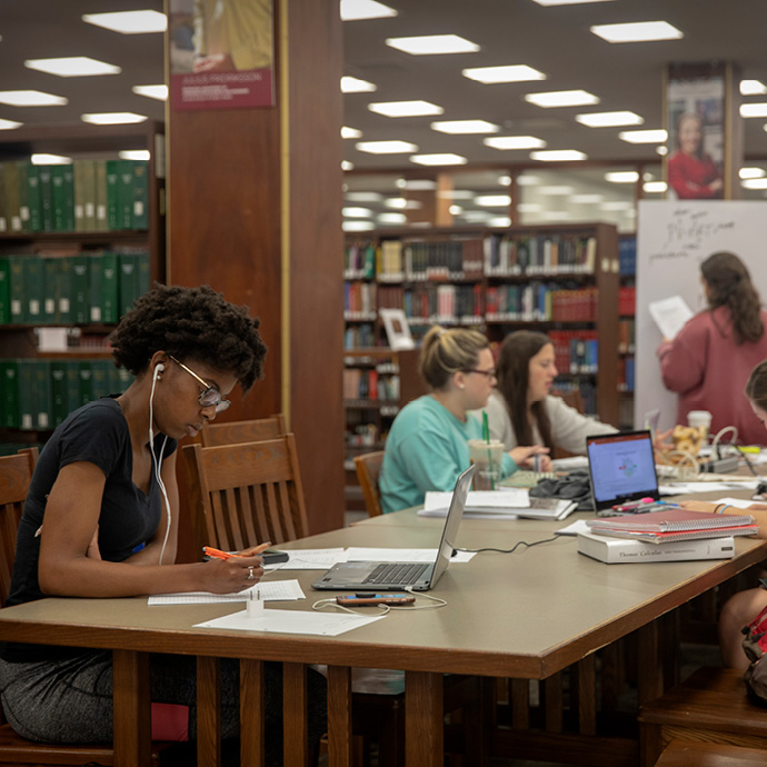 A group of women studying at a wooden table in Thomas Cooper Library