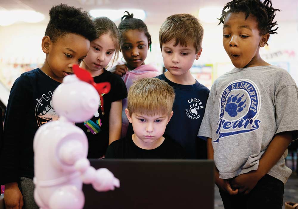 Elementary school students gather around a computer that is working with ABii, Boccanfuso’s educational robot.