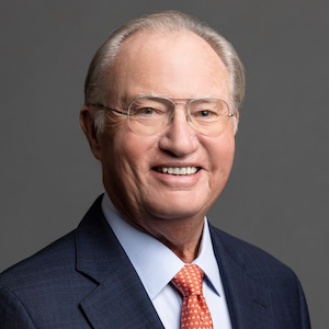 man in blue blazer and reddish tie smiling