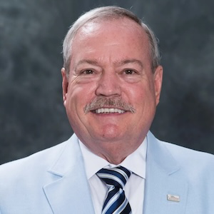 man in blue suit and blue tie smiles