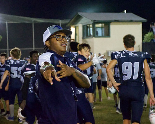 Jarett Mayfield poses at a field with his football team.