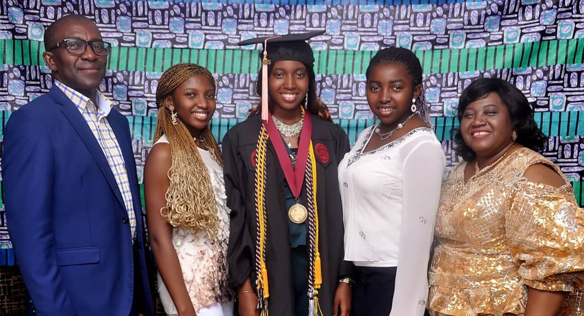 A father and mother stand with three daughters. The center daughter wears a graduation cap and gown from USC.