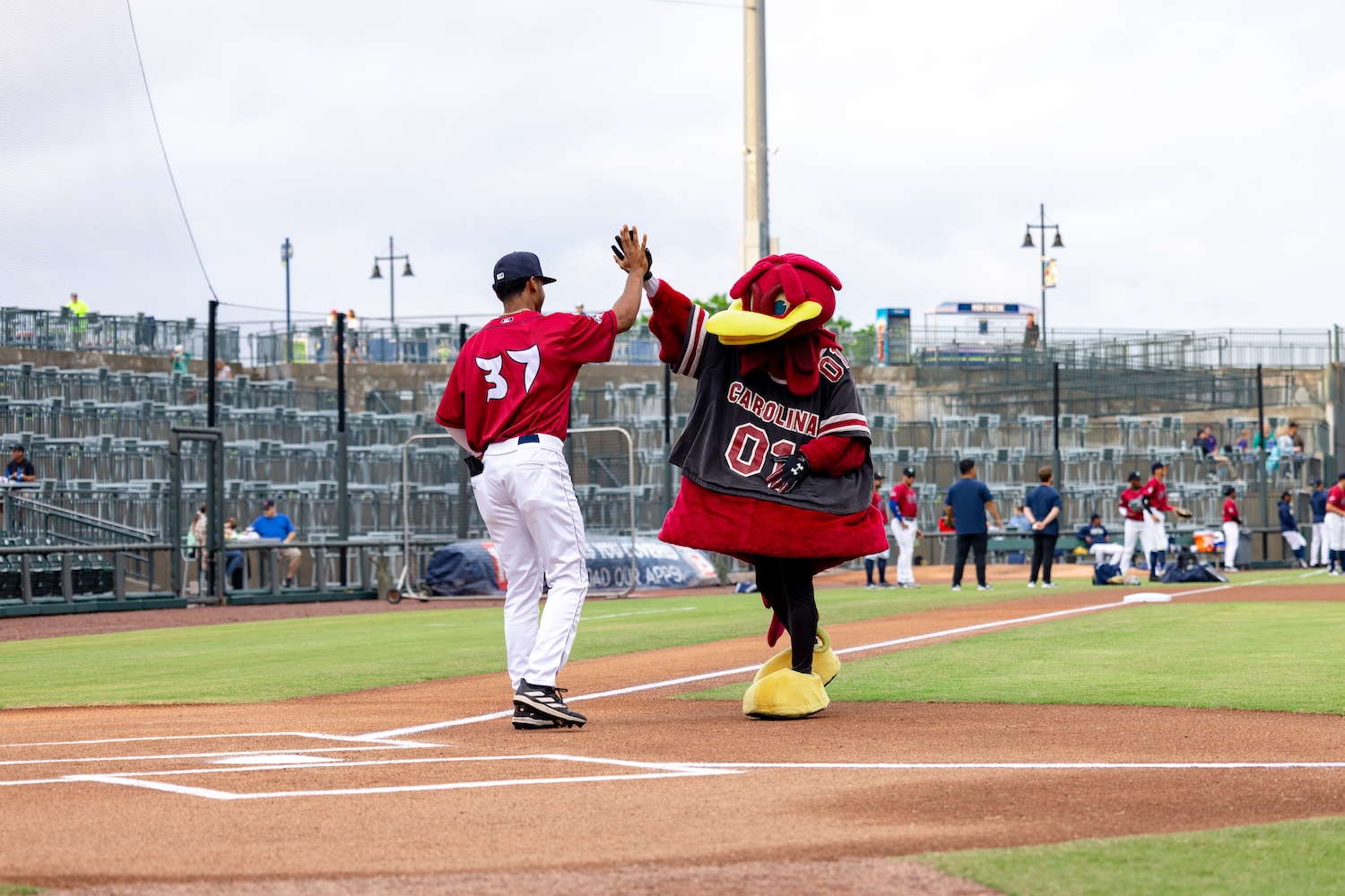 A man holding a small child smiling with Cocky at Segra Park.