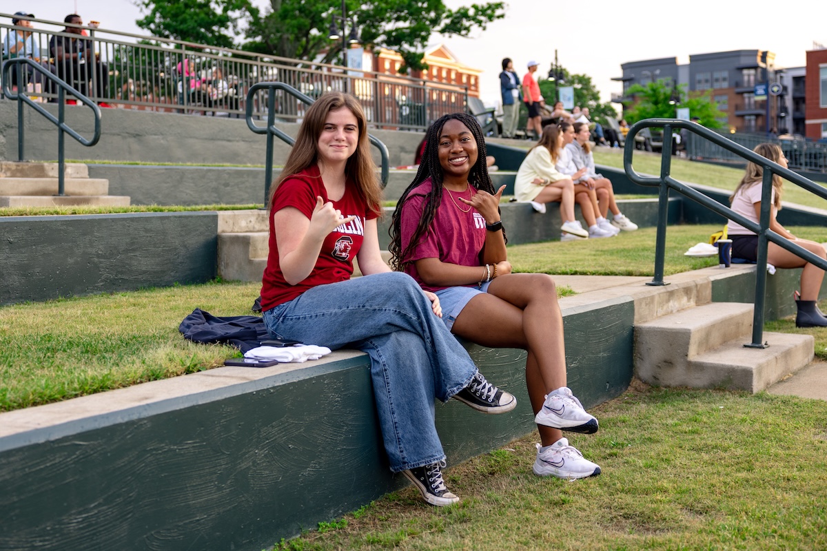 Two girls at USC Night at the Fireflies smiling and doing a spurs up.