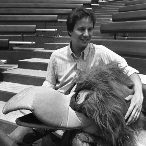 John Routh poses with the Cocky head in a black and white photo.